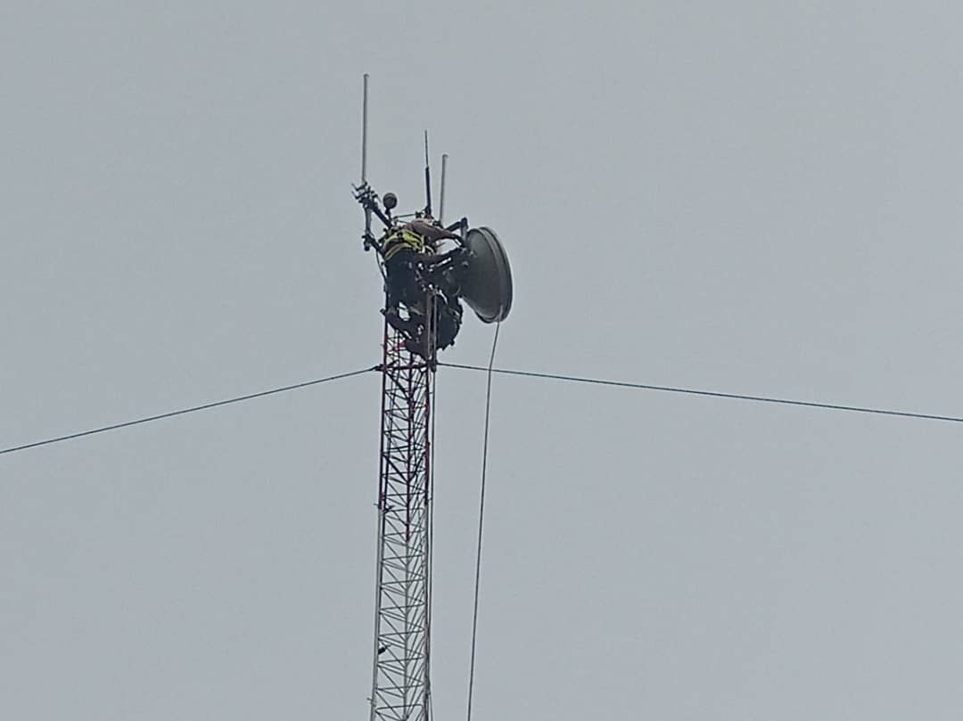 Technicien au sommet d'un pylône télécom installant une antenne